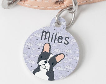 Puede incluir: Una chapa redonda para perro, de color morado, con una ilustración de bulldog francés blanco y el nombre "Miles" impreso en negro.