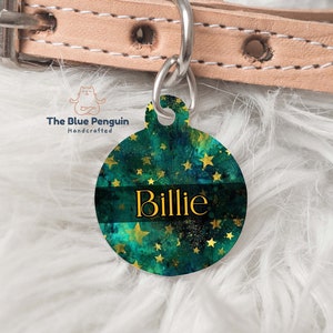 Puede incluir: Chapa redonda para perro de color verde y dorado con estrellas doradas y el nombre "Billie" impreso en una banda negra. La chapa está unida a un collar de perro de cuero marrón claro.