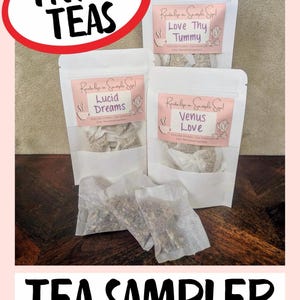 Könnte beinhalten: Ein Tee-Sampler mit drei weißen Beuteln mit den Aufschriften "Love Thy Tummy", "Lucid Dreams" und "Venus Love". Das Bild enthält den Text "Try 3 Teas" und "Tea Sampler". Jeder Beutel enthält Teebeutel.