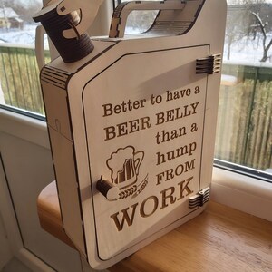Puede incluir: Caja de madera con forma de bid&oacute;n de gasolina con una puerta con bisagras y un asa. La caja est&aacute; decorada con una jarra de cerveza y el texto "Better to have a BEER BELLY than a hump FROM WORK".