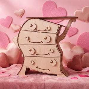 May include: A whimsical wooden dresser with four drawers, featuring a smiling face design. The light-colored wood contrasts with the pink background and heart-shaped decorations. A decorative piece for a bedroom or nursery.