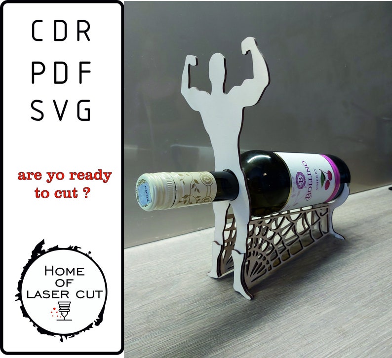 May include: A laser cut wooden wine bottle holder shaped like a muscular figure with arms raised. The holder is holding a bottle of wine with a white label and a pink and white label. The text "BOLLINO" is visible on the label.