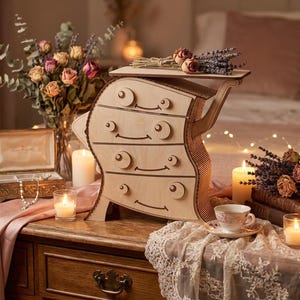 May include: A wooden decorative dresser with four drawers and a top shelf, adorned with curved edges and circular drawer pulls. The dresser is set on a wooden table with candles, flowers, and a jewelry box. The scene is lit with warm, soft lighting.