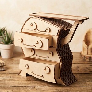 May include: A whimsical wooden dresser with four drawers, each featuring a smiling face design. The dresser has a unique, curved shape and a small top shelf. The back of the dresser has a textured, brown pattern. The dresser is made of light-colored wood.