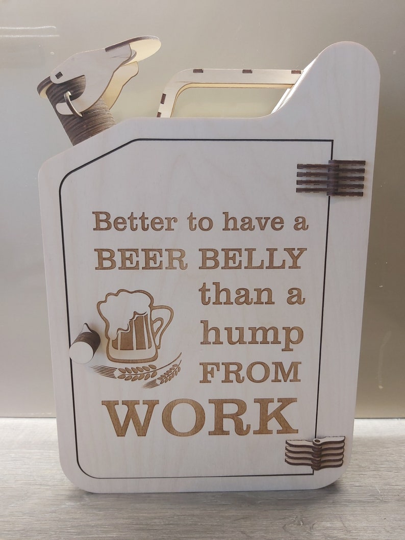 Puede incluir: Caja de madera con forma de bid&oacute;n de gasolina con una puerta con bisagras. La puerta tiene un jarro de cerveza y espigas de trigo grabadas. El texto en la caja dice "Better to have a BEER BELLY than a hump FROM WORK".