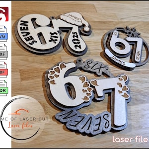 Puede incluir: Adornos de madera cortados con láser con los números 67, con las palabras "Six" y "Seven". Un adorno tiene un gorro de Papá Noel con el nombre "James" y el año "2025". Otro tiene un diseño de copo de nieve.