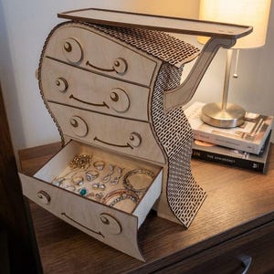 May include: A whimsical wooden jewelry chest with four drawers and a top shelf. The chest is light-colored with a unique design, featuring curved lines and decorative cutouts. The open drawer reveals various jewelry pieces.