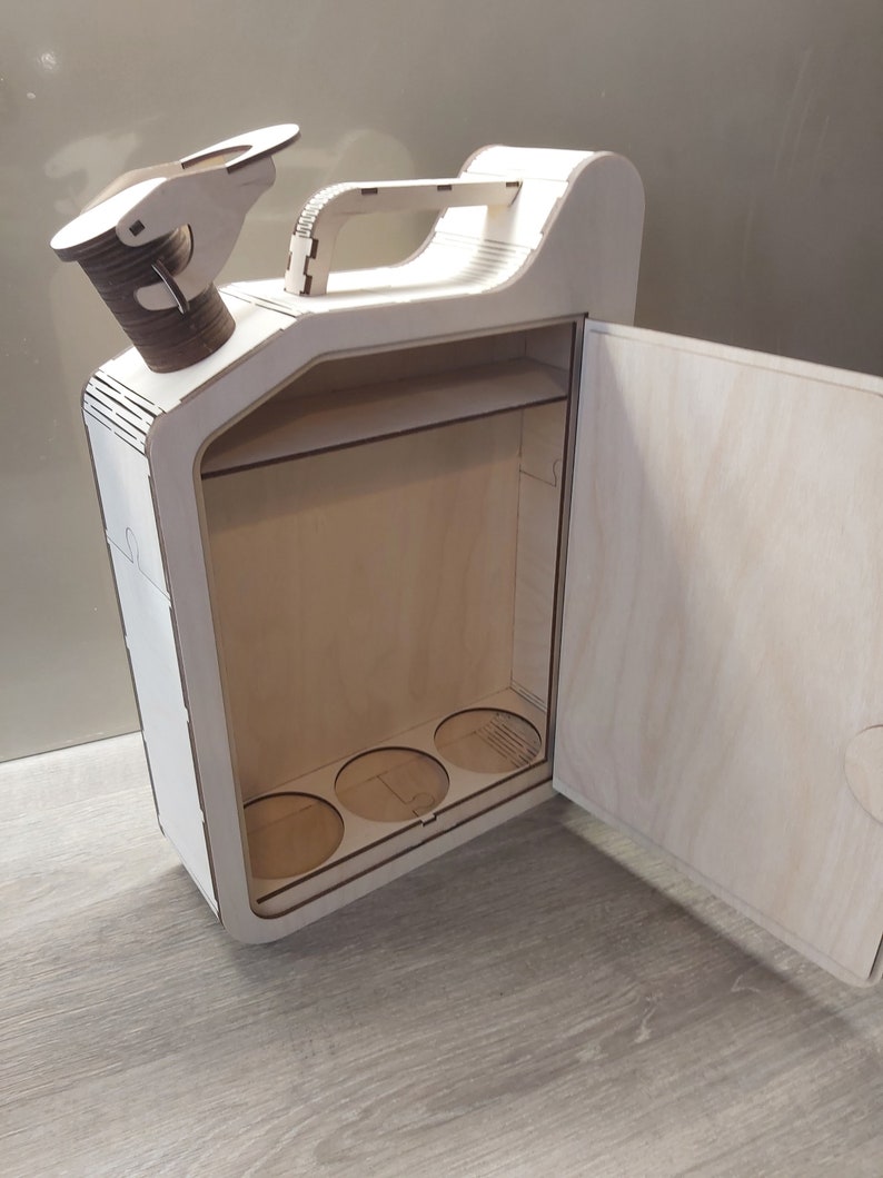 Puede incluir: Una caja de madera con forma de bid&oacute;n de gasolina con una puerta con bisagras y un asa. La caja tiene un estante y cuatro recortes circulares en la parte inferior. La caja est&aacute; hecha de madera clara y tiene un acabado natural.