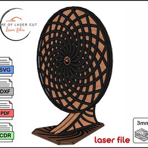 Può includere: Una scultura in legno tagliata al laser con un design a spirale. La scultura è nera e marrone, con un motivo circolare. La base e il supporto sono anch'essi in legno. L'immagine include il testo "Home of Laser Cut Laser files" e "laser file".