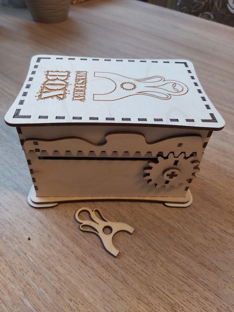 May include: A wooden box with a decorative design and a small gear on the side. The box has a slot on the top and the text "WISHERRY BOX" is engraved on the lid.