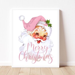 Pu&ograve; includere: Una stampa natalizia in stile vintage con un Babbo Natale di cartone animato con un cappello e una barba rosa. Il testo "Merry Christmas" &egrave; scritto in lettere corsive rosa.