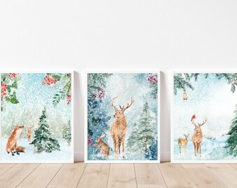 May include: Three framed watercolor prints featuring winter forest scenes. The prints depict a fox, deer, and rabbit in a snowy landscape with evergreen trees and red berries. The artwork has a soft, dreamy quality.