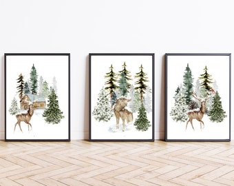 May include: Set of three framed art prints featuring watercolor illustrations of winter scenes. Each print showcases a different forest scene with deer, a wolf, and a cabin, all set against a backdrop of snow-covered trees in shades of green and white.