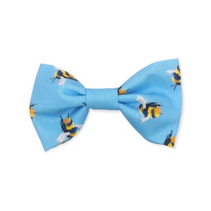 May include: A light blue bow tie with a pattern of yellow and black bumblebees.