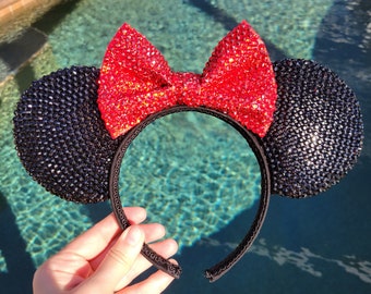 Peut inclure: Des oreilles de Minnie Mouse noires scintillantes avec un nœud rouge scintillant. Les oreilles sont faites de strass et le nœud est fait de paillettes.