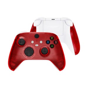 May include: A red transparent Xbox controller with white buttons and a white Xbox controller in the background.