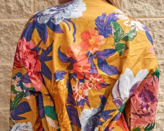 Könnte beinhalten: Eine gelbe Robe mit floralem Muster in Blau, Grün und Rot.