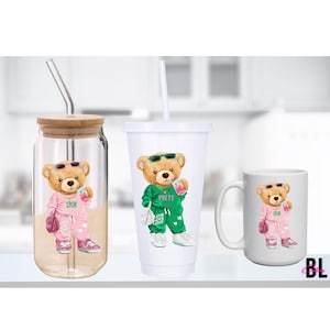 Puede incluir: Tres artículos de cristalería: una lata de vidrio con tapa de bambú, un vaso de plástico blanco y una taza blanca. Cada uno presenta un oso de peluche de dibujos animados con gafas de sol y un chándal. El oso sostiene una bebida y un bolso.