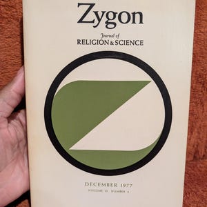 May include: A cream-coloured journal titled Zygon Journal of Religion & Science, dated December 1977, Volume 12, Number 4. The cover features a large black circle containing a green geometric shape and a white triangle on a plain background.