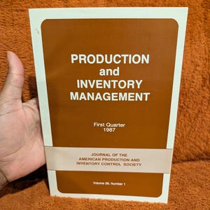 May include: A softcover journal titled Production and Inventory Management, First Quarter 1987, Volume 28, Number 1. The cover is brown with white text and a white border, published by the American Production and Inventory Control Society.