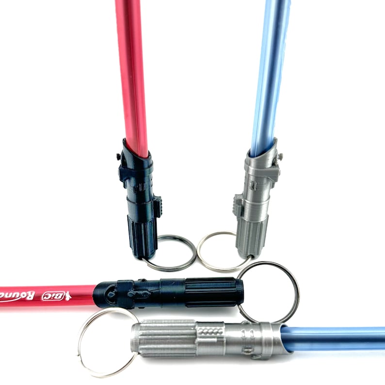 May include: Three lightsaber keychains, one red, one blue, and one black. The keychains are attached to silver key rings. The red keychain has the text "Big Round" on it.