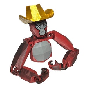 May include: A red articulated toy monkey wearing a gold cowboy hat. The monkey has a gray chest and black eyes.