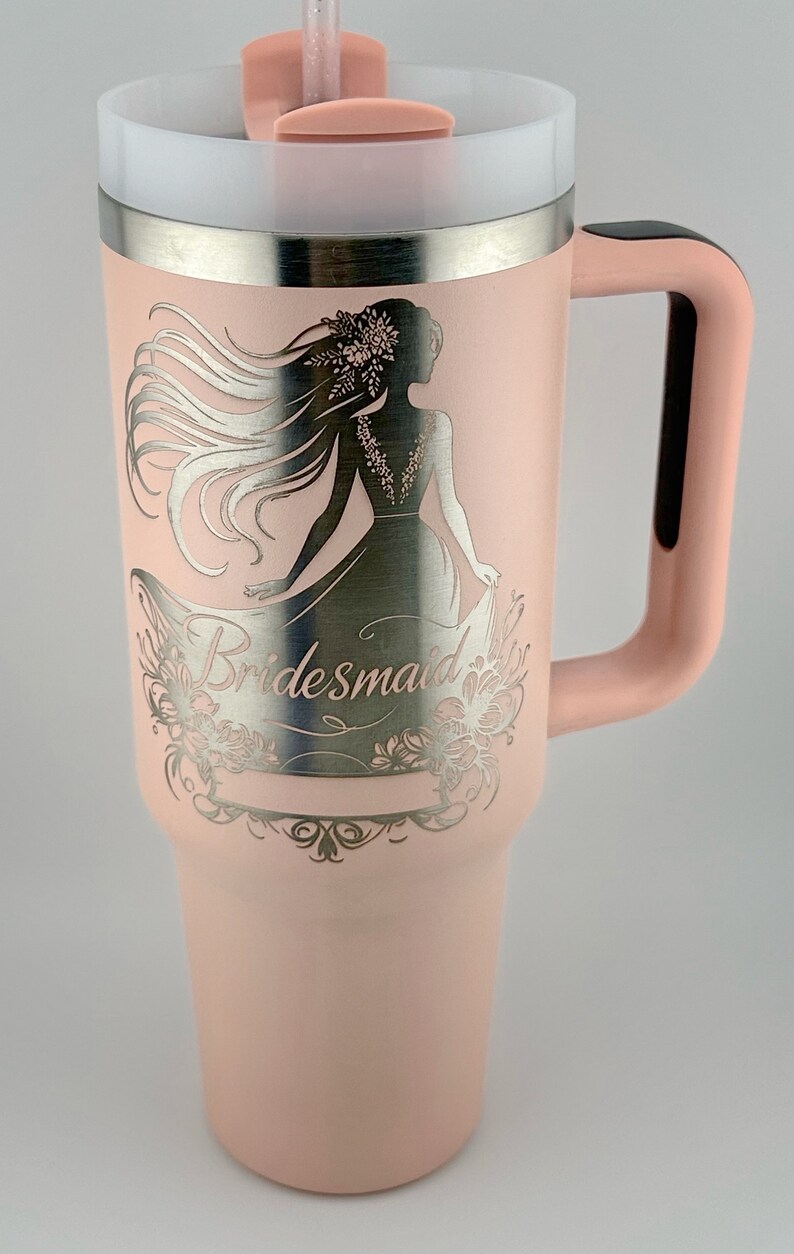 May include: A pink stainless steel tumbler with a silver design of a woman in a dress and the word "bridesmaid".
