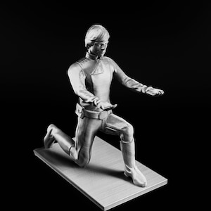 May include: A 3D printed figurine of a character from Star Wars kneeling with arms outstretched. The figurine is made of a light gray plastic and is posed in a dramatic action pose.