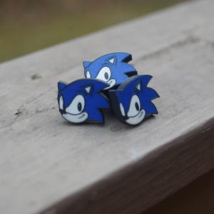 May include: Three blue and black 3D printed Sonic the Hedgehog figurines. The figurines are facing different directions and are arranged in a triangular shape.
