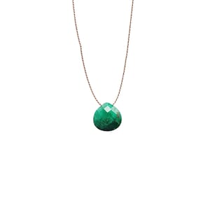 Puede incluir: Un collar con un colgante de piedra preciosa verde en un cordón marrón.