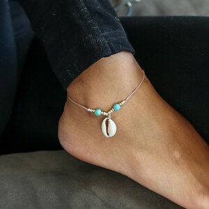 以下が含まれることがあります： 小さな白い貝殻のチャームとターコイズビーズが付いた繊細なアンクレットです。