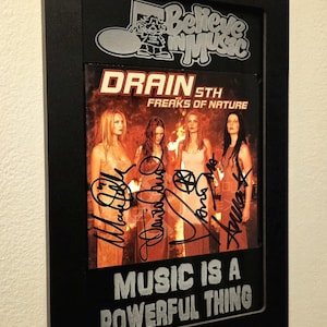 May include: Black framed print featuring the album cover for Drain 5th's "Freaks of Nature" with band member signatures. The print includes the text "Music is a Powerful Thing" and a "Believe in Music" logo.