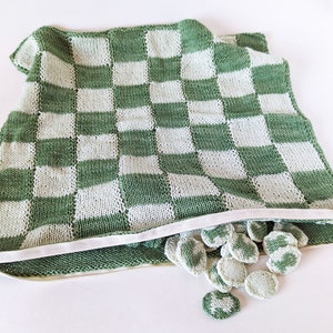 May include: A green and white knitted checkerboard bag with a zipper opening and green and white checkers spilling out.