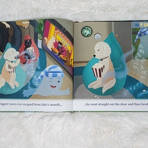 Pu&ograve; includere: Un libro aperto con due illustrazioni di cani in poltrone a sacco che guardano un film su uno schermo televisivo. Il testo sullo schermo recita "Feline Feud". Il testo sulla pagina recita "The biggest yawn ever escaped from Jake's mouth... ...he went straight out the door and then headed south."