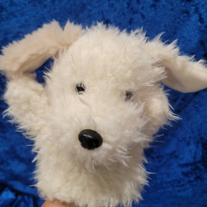 Pu&ograve; includere: Marionetta di cane di peluche bianca con occhi neri e naso nero. La marionetta ha orecchie floppy ed &egrave; fatta di materiale morbido e soffice.