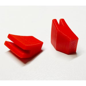 Pu&ograve; includere: Due pezzi di plastica rossa, uno con una forma curva e l'altro con una forma appuntita. Entrambi i pezzi hanno una fessura al centro.