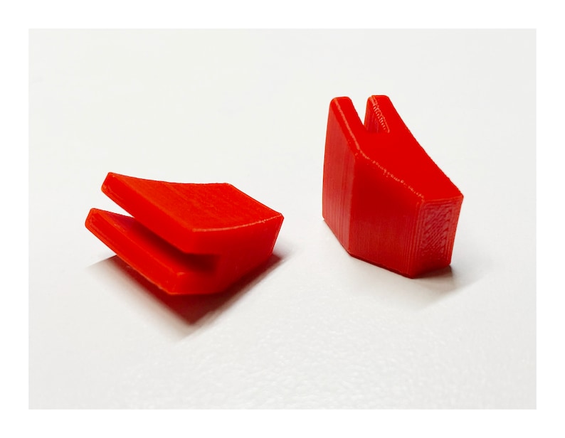 Pu&ograve; includere: Due pezzi di plastica rossa, uno con una forma curva e l'altro con una forma appuntita. Entrambi i pezzi hanno una fessura al centro.