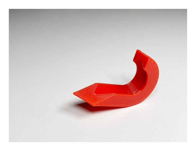 May include: A bright red plastic 3D printed hook with a curved shape.