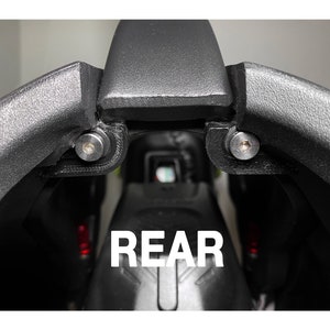 May include: Close-up of the rear of a black motorcycle seat with the word "REAR" printed in white letters.