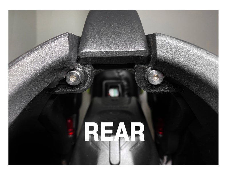 May include: Close-up of the rear of a black motorcycle seat with the word "REAR" printed in white letters.