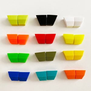 Pu&ograve; includere: Dodici paia di piccoli pezzi di plastica triangolari in vari colori, tra cui verde, blu, rosso, giallo, arancione, nero, bianco e marrone. I pezzi sono disposti in quattro file di tre paia ciascuna.
