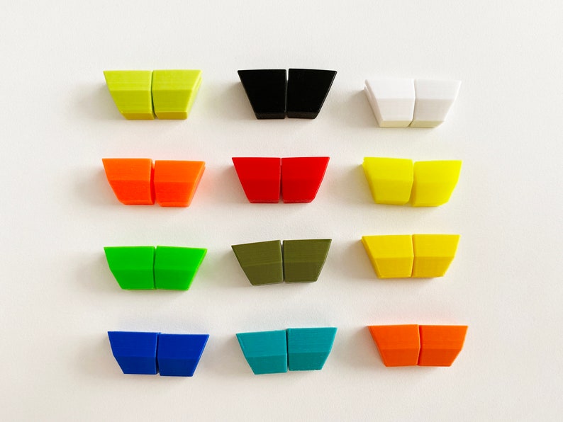 Pu&ograve; includere: Dodici paia di piccoli pezzi di plastica triangolari in vari colori, tra cui verde, blu, rosso, giallo, arancione, nero, bianco e marrone. I pezzi sono disposti in quattro file di tre paia ciascuna.