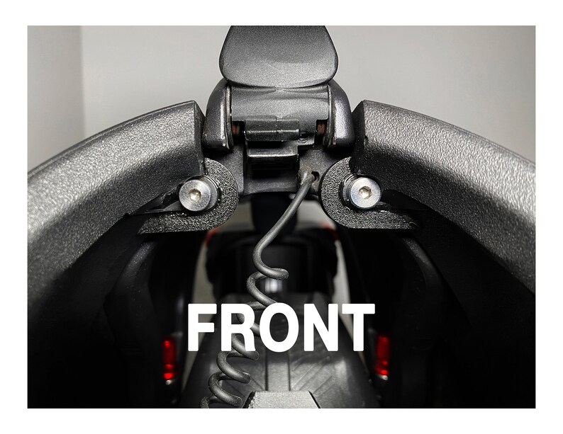 May include: Close-up of a black camera case with a hinge and two silver screws. The case is open and the word "FRONT" is visible in white letters.