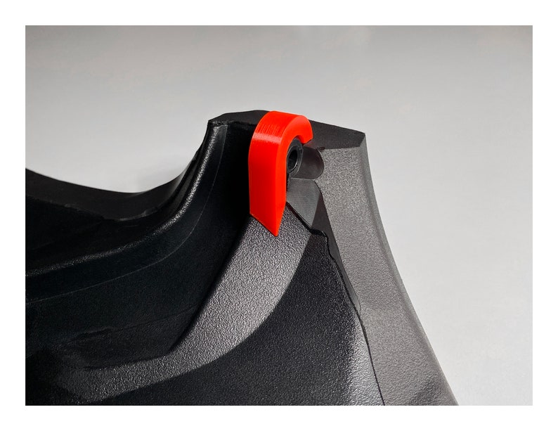 May include: Close-up of a black and gray plastic object with a red plastic tab. The tab is attached to the object with a small black screw.