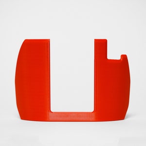 May include: A bright red plastic phone stand with a curved base and a raised section for holding a phone.