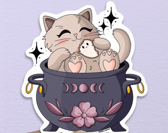 May include: A sticker featuring a cartoon cat in a cauldron. The cat is light brown with pink accents, sitting in a dark purple cauldron decorated with crescent moons and a pink flower. Gold handles and star accents complete the design.