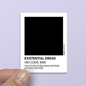 May include: A white sticker with a black square and text that reads "EXISTENTIAL DREAD, HEX CODE: #000, THE COLOR OF REALIZING NOTHING ACTUALLY MATTERS." The sticker is held by a hand.