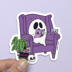 May include: A sticker featuring a cartoon ghost reading a book while seated in a purple armchair. A gray cat peeks over the chair's arm. A stack of books, a small skull, and a potted plant are next to the chair. The sticker has the text "DOODLE WITCH".