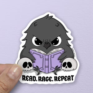 以下が含まれることがあります： 怒った表情のカラスの漫画のステッカー。紫色の本を読んでおり、2つの頭蓋骨に挟まれています。「READ. RAGE. REPEAT」というテキストがカラスの下にあります。