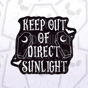 以下が含まれることがあります： 「KEEP OUT OF DIRECT SUNLIGHT」のテキストが入った白黒ステッカー。三日月と星が付いた棺のイラストが2つと、コウモリのシルエットがデザインされています。ゴシック調のテーマです。